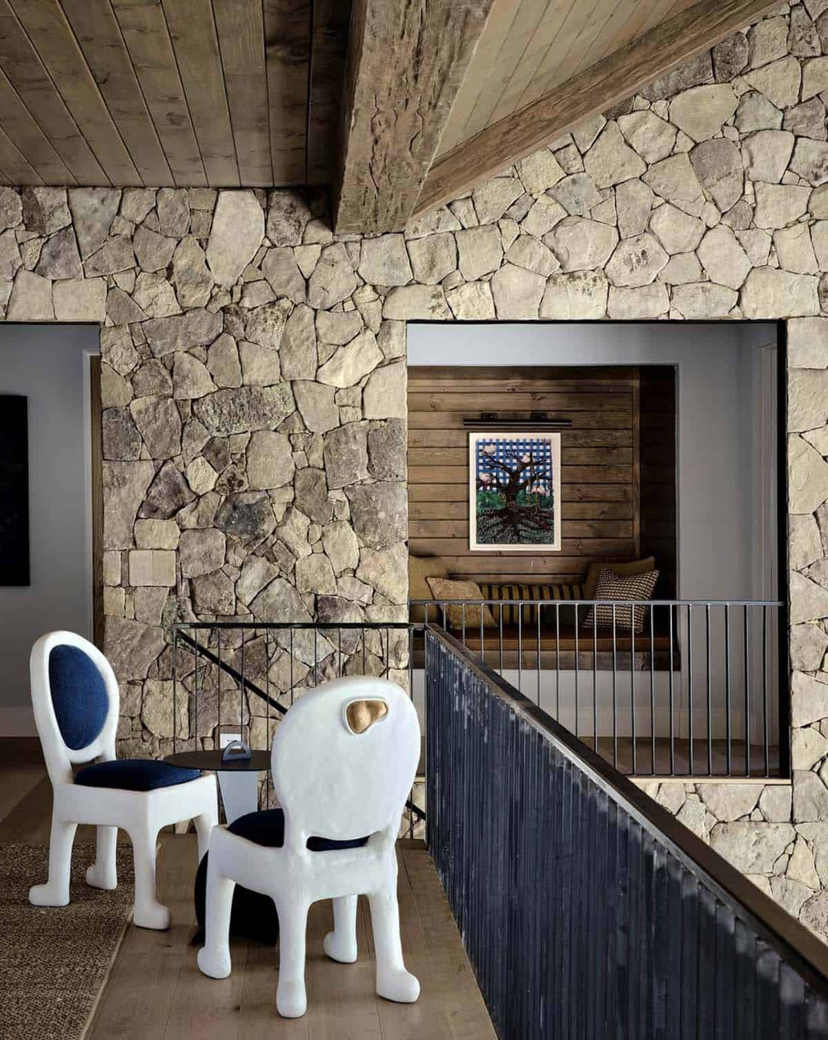 Stone stairwell landing with sculptural white chairs and reading nook