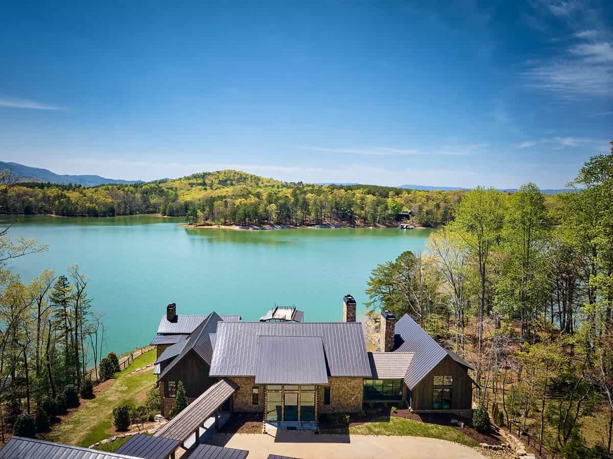 Aerial view of lake house nestled among trees along turquoise water
