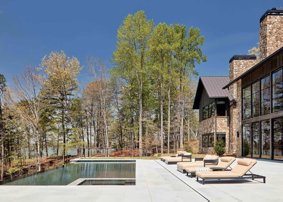 Backyard infinite edge pool with lounge chairs beside stone chimney