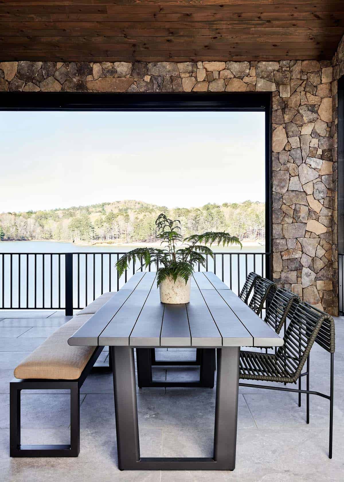 Covered porch dining table with woven chairs overlooking the lake
