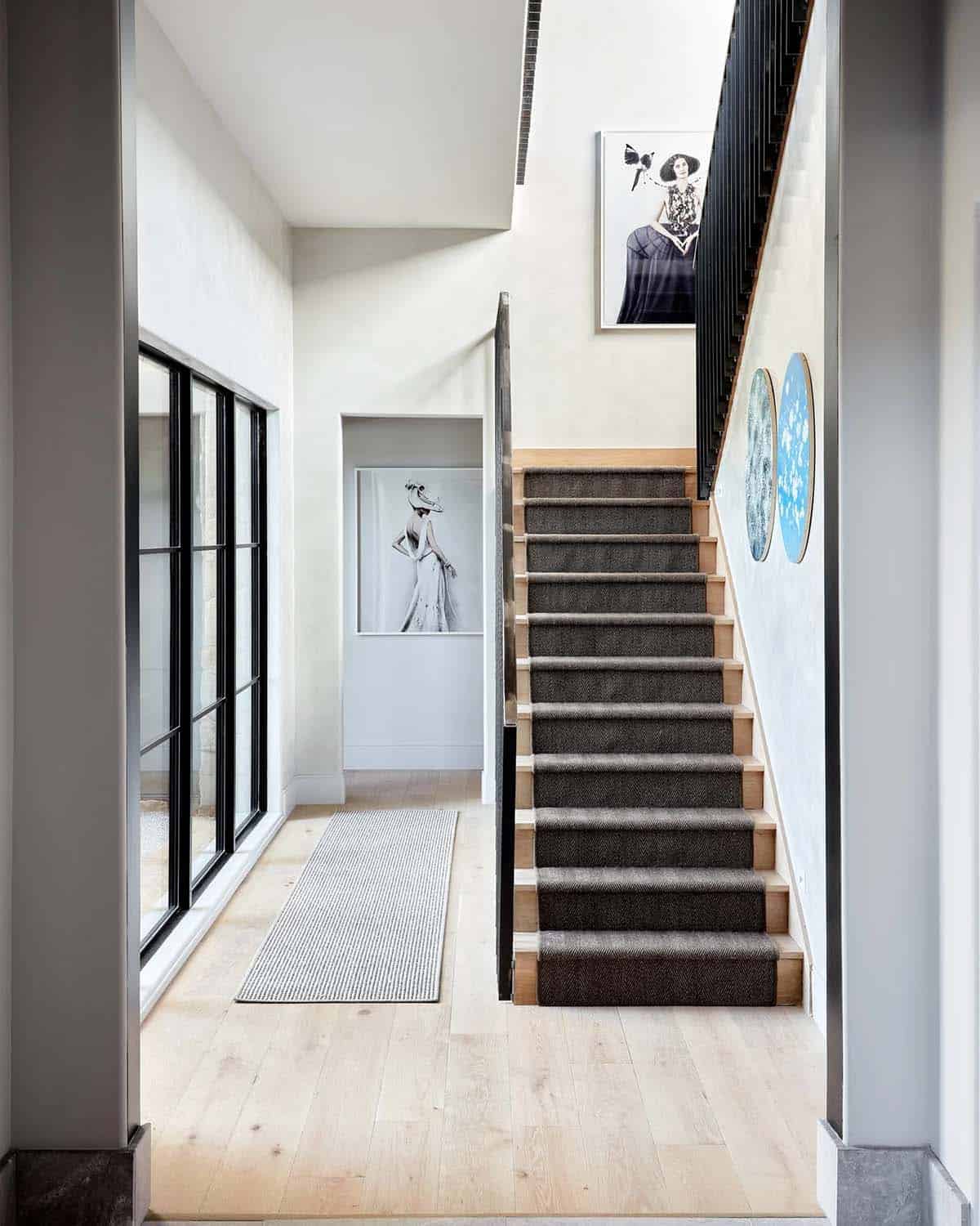 Entry hallway with striped stair runner and black and white fashion prints