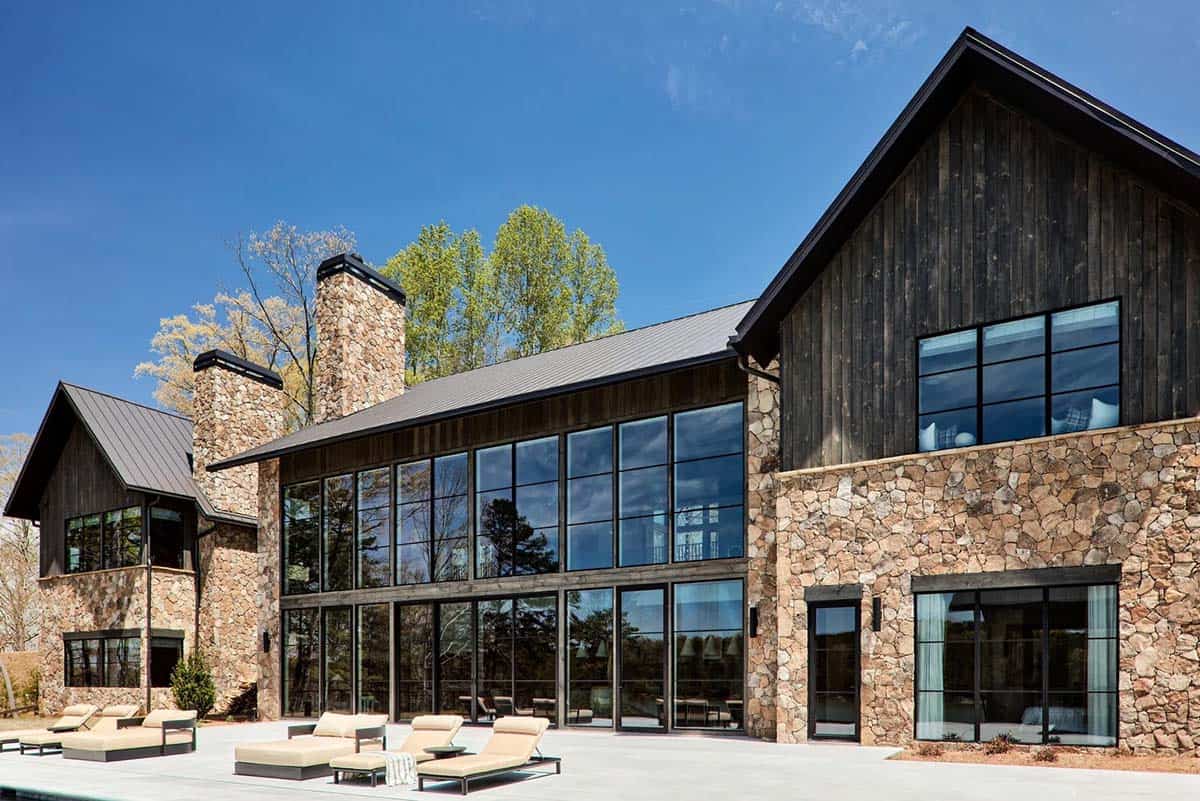 Rear exterior view of stone and wood clad lake house with pool patio