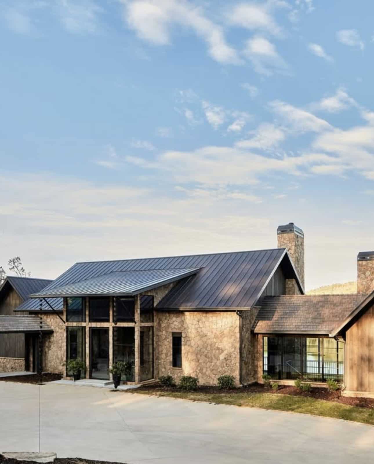 Front exterior of rustic stone and wood lake house with covered entry