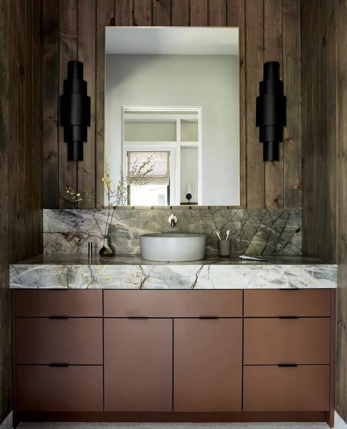 Terracotta vanity with vessel sink and green marble backsplash in bathroom