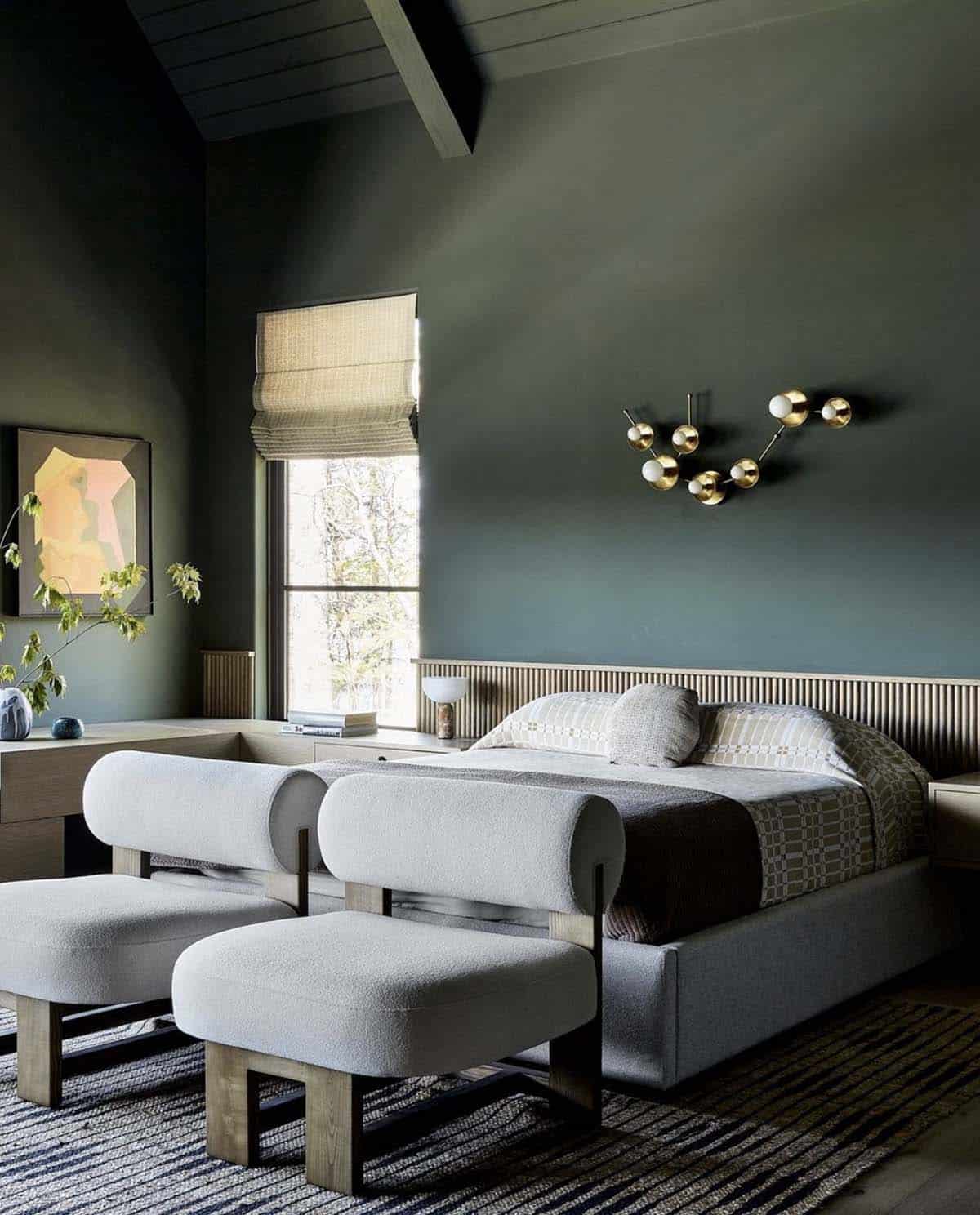 Dark green guest bedroom with fluted headboard and sculptural gold sconce
