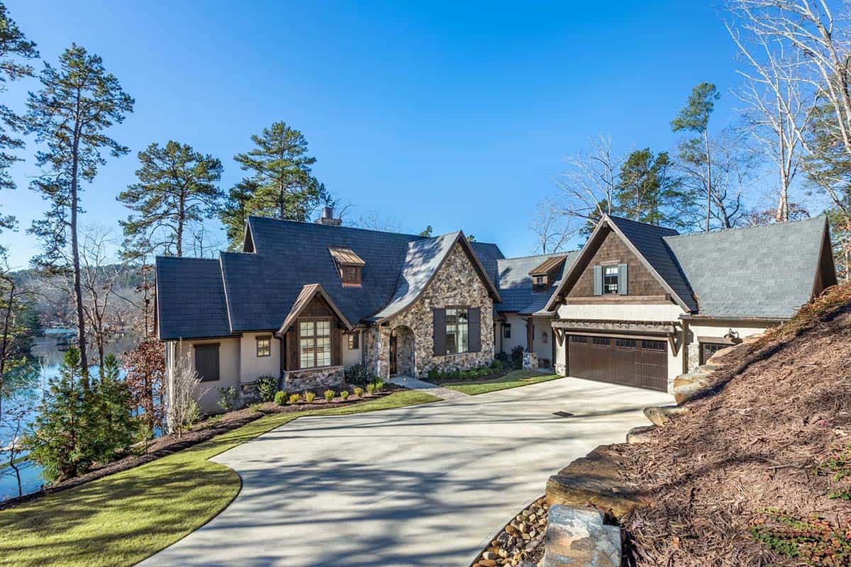 Stone and shingle lakefront home exterior with circular driveway and lake views