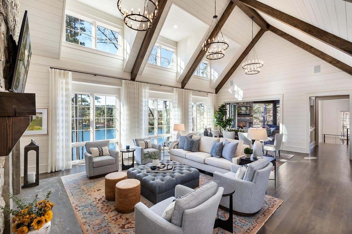 Living room with vaulted shiplap ceiling, wood beams, and gray seating around tufted ottoman
