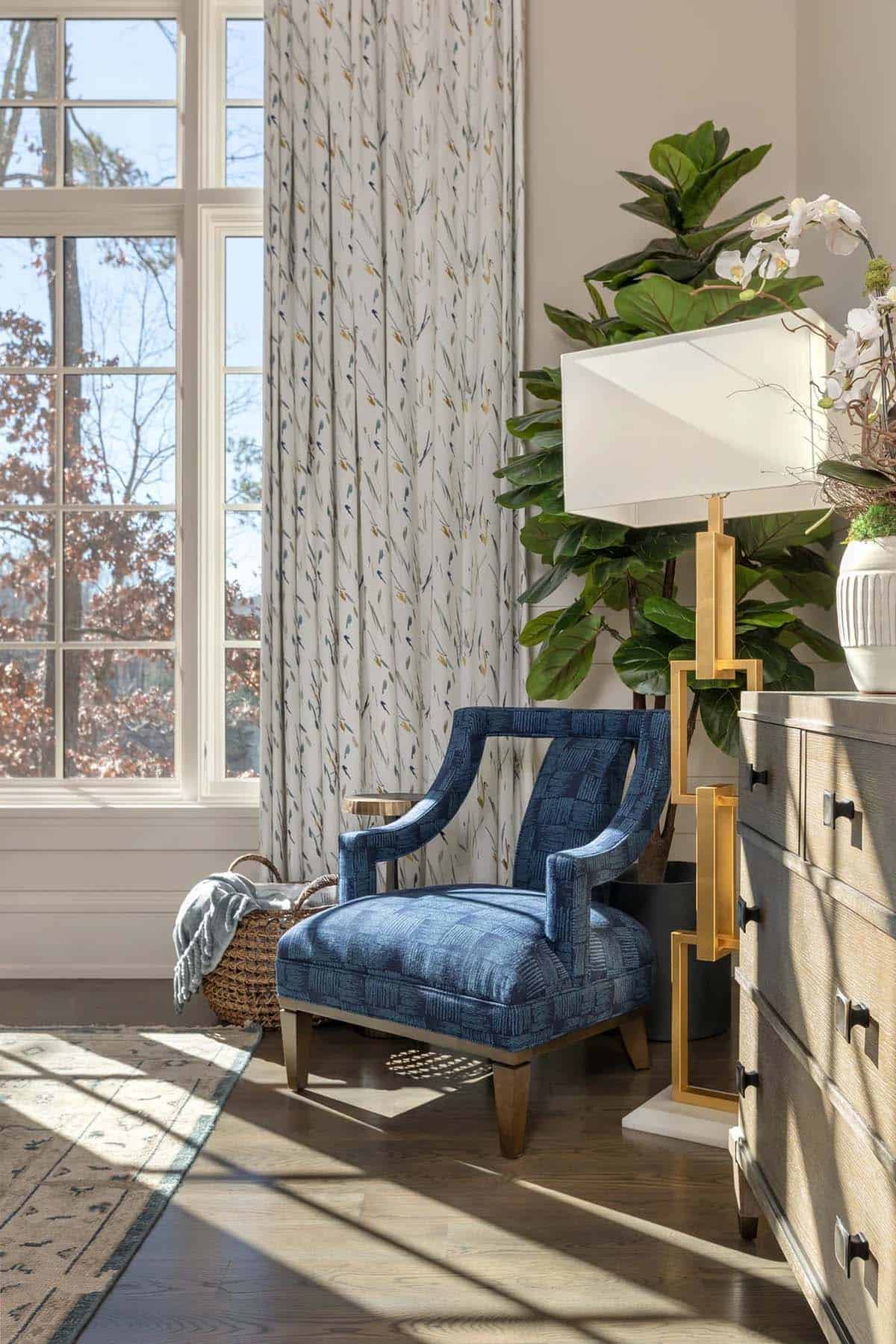 Bedroom corner with blue patterned armchair, gold floor lamp, and fiddle-leaf fig