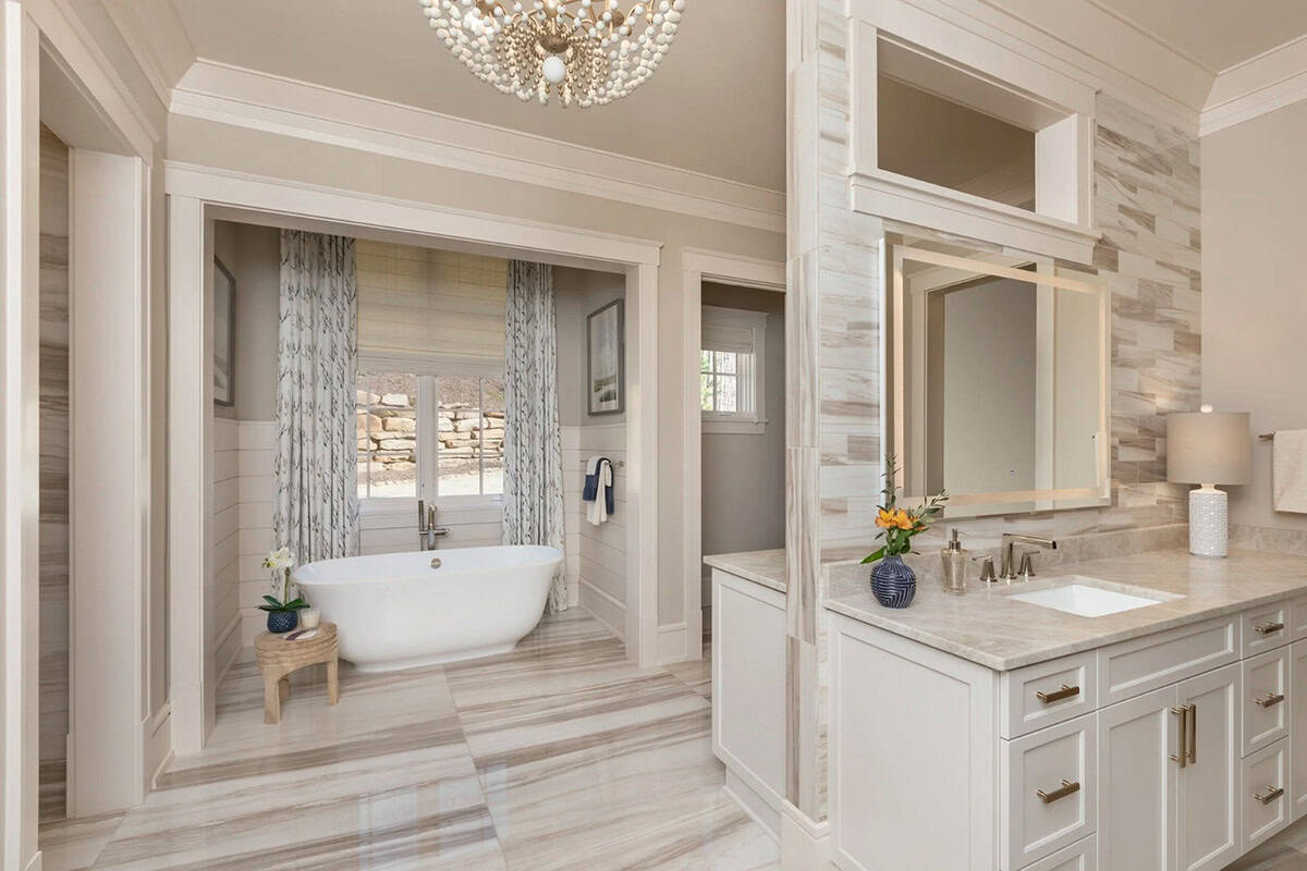 Primary bathroom with freestanding tub alcove and marble-tiled vanity area