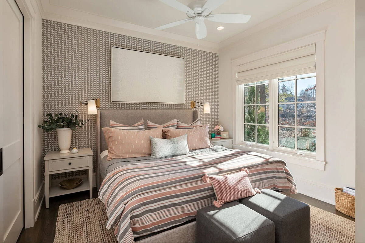 Bedroom with geometric wallpaper accent wall and striped pink and gray bedding