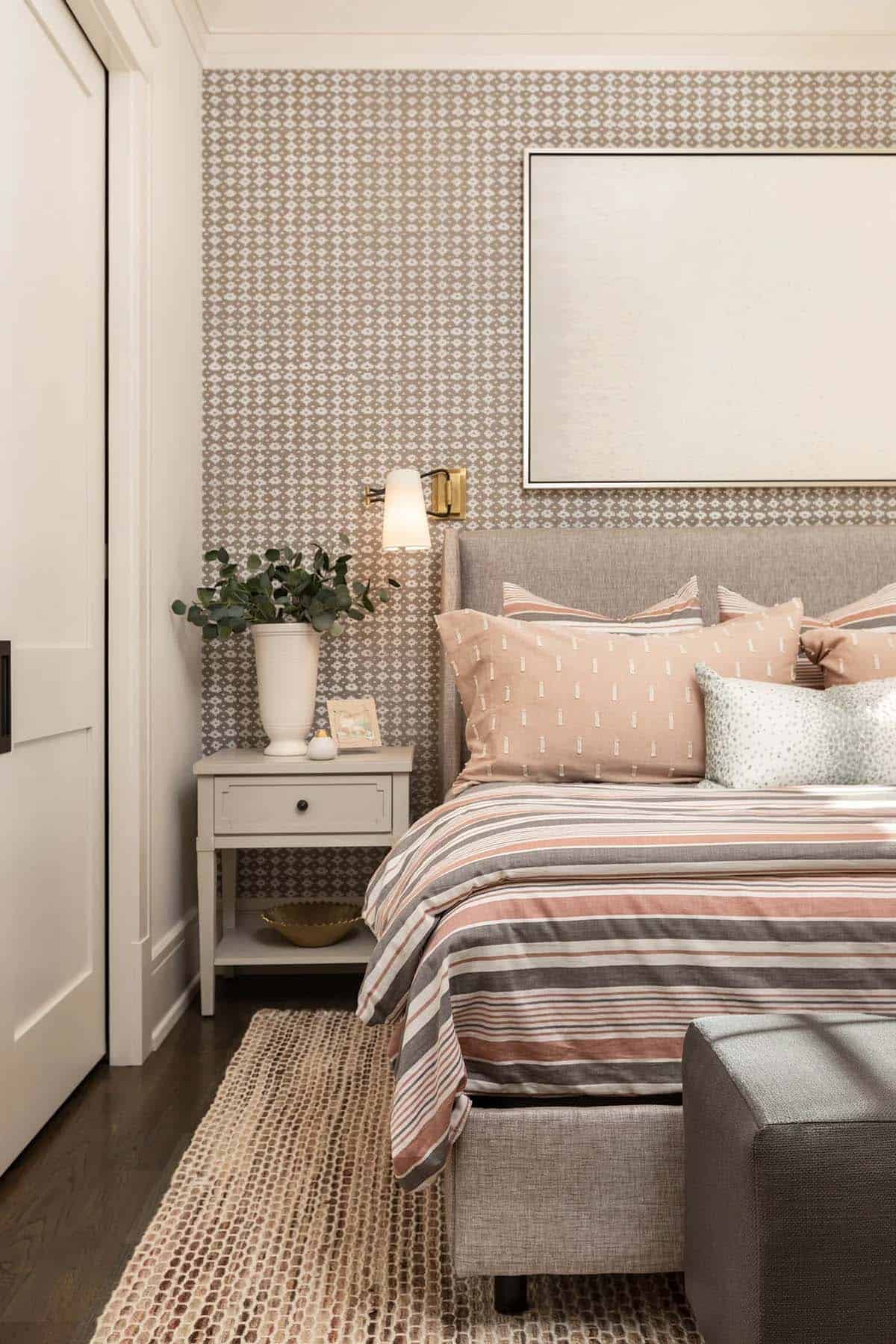 Close-up of bedroom nightstand with sconce light and striped bedding