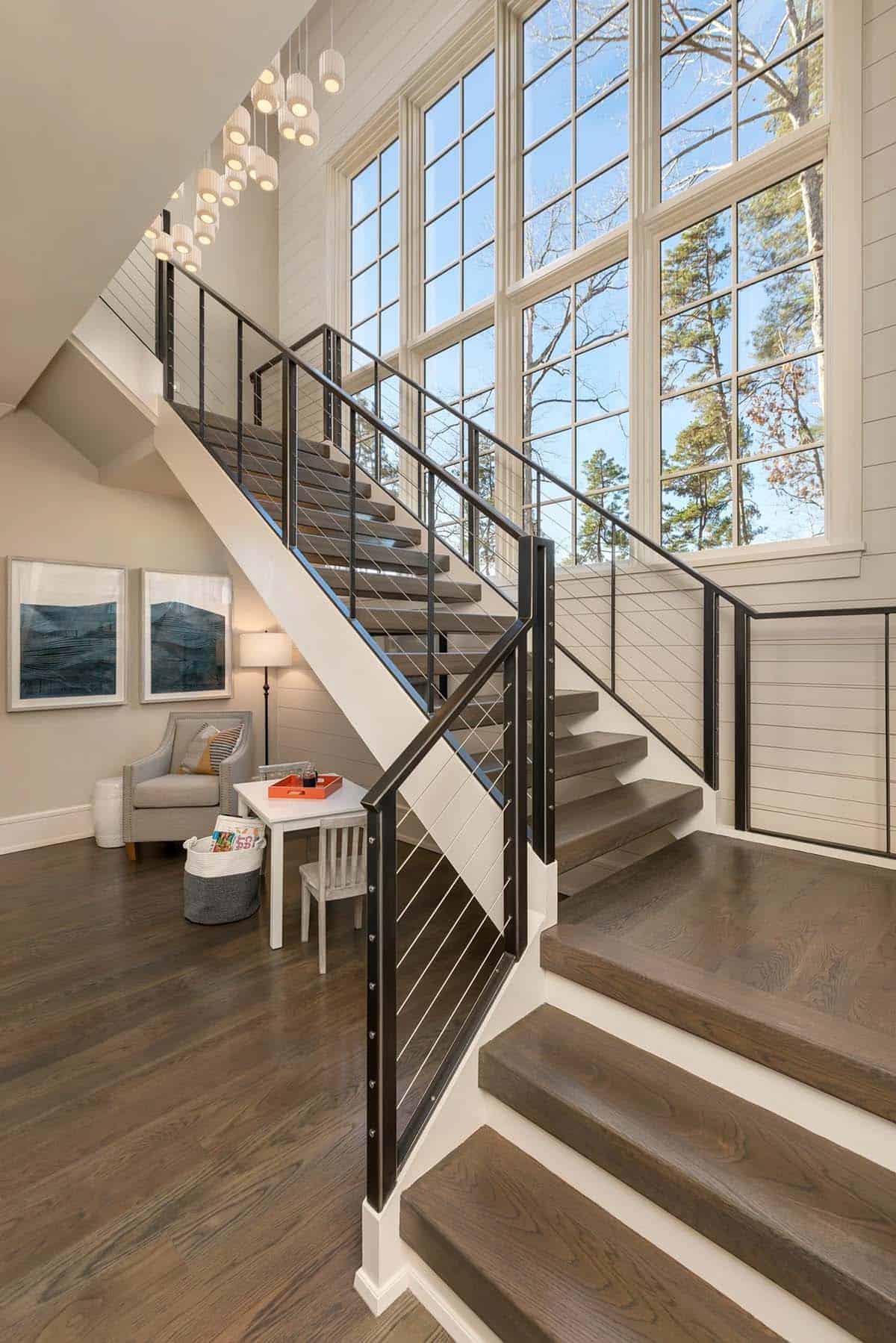 Open staircase with cable railings beneath tall multi-pane windows
