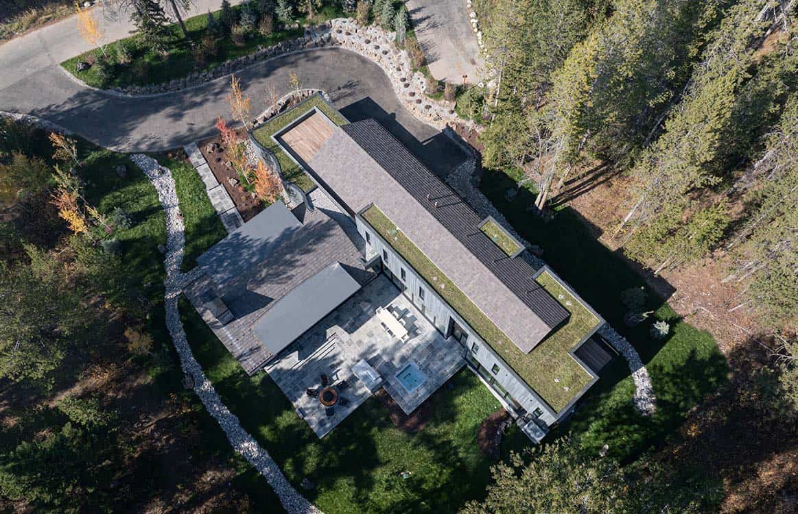 Aerial view of the home's sprawling roofline, green roof sections, and forested mountain lot