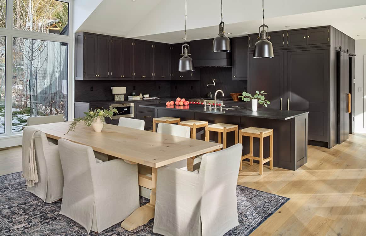 Open kitchen and dining area with matte black cabinetry and wood farmhouse table