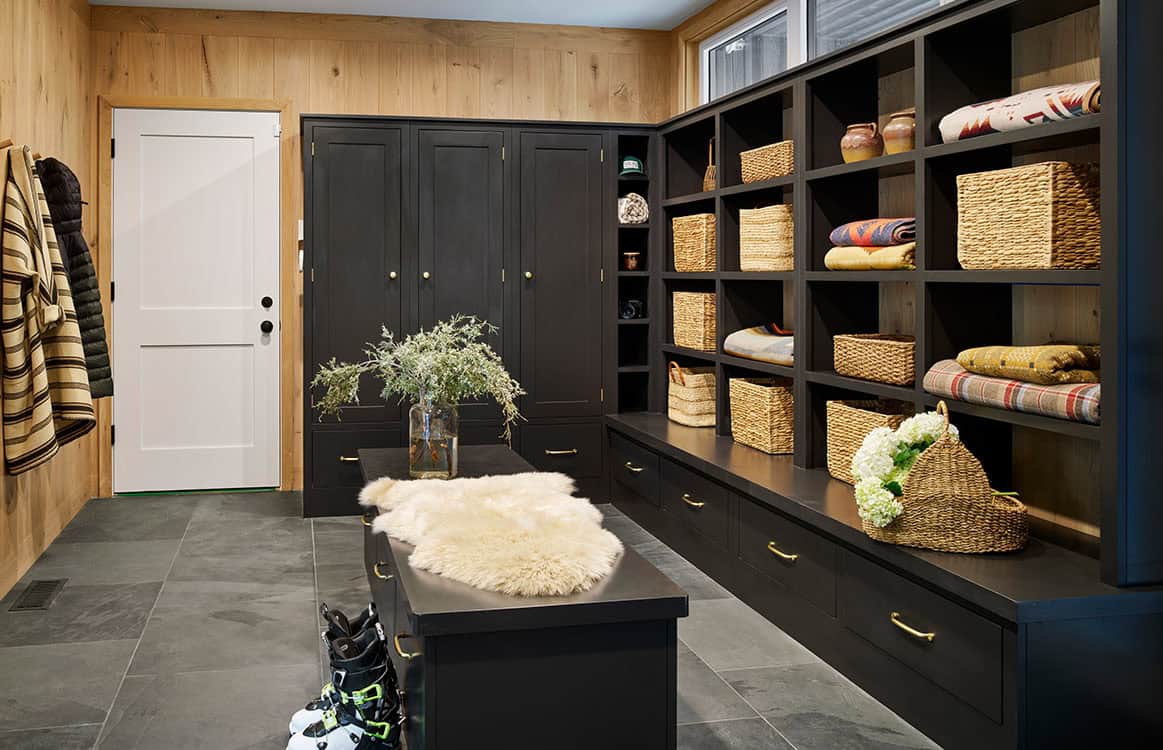 Mudroom with black built-in cabinetry, woven baskets, and wood-paneled walls
