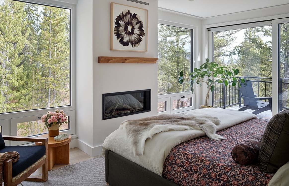 Primary bedroom with corner fireplace, wall art, and glass doors to a private balcony