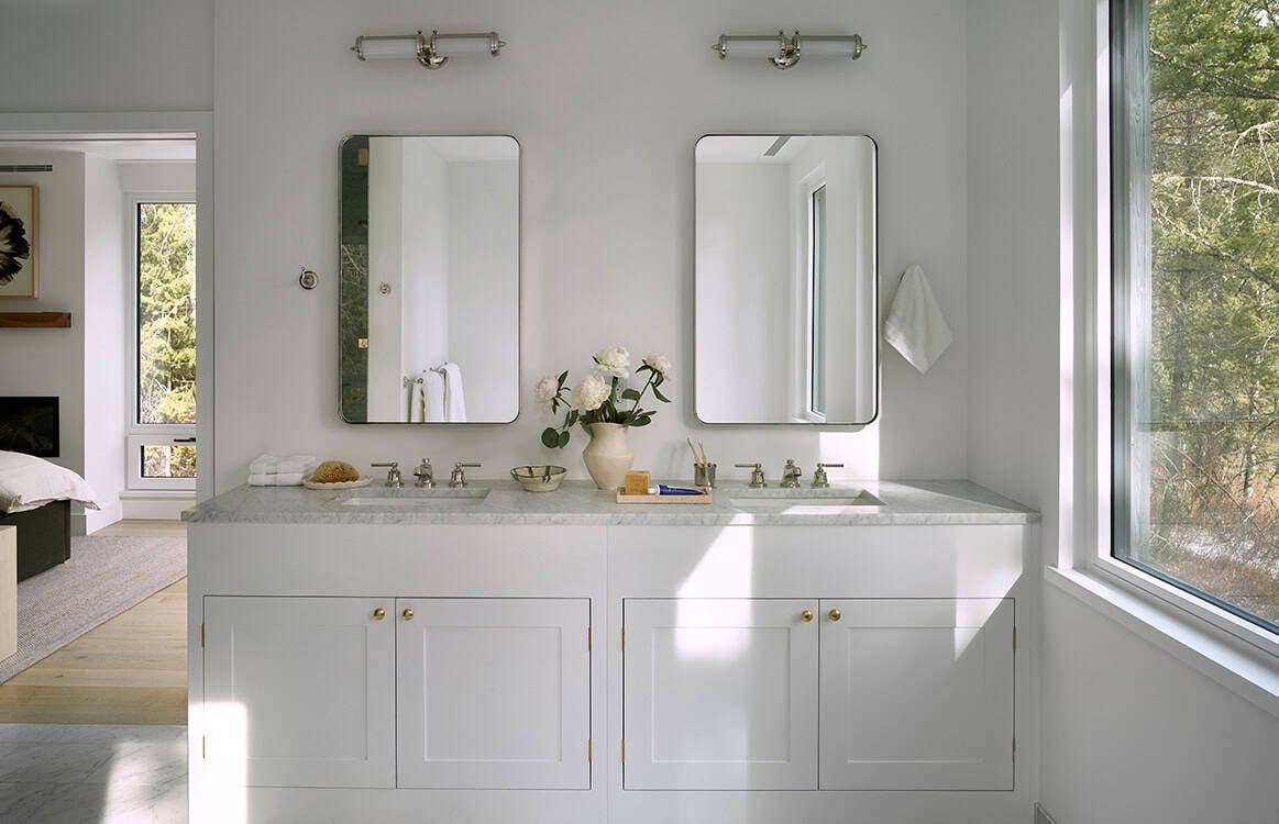 White double vanity bathroom with marble countertop and round mirrors