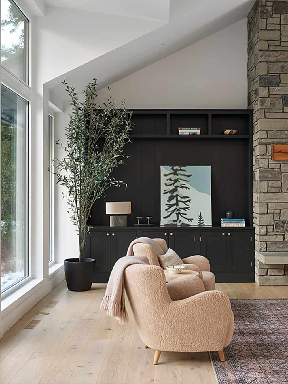 Sitting area with black built-in cabinetry, stone fireplace column, and boucle armchairs