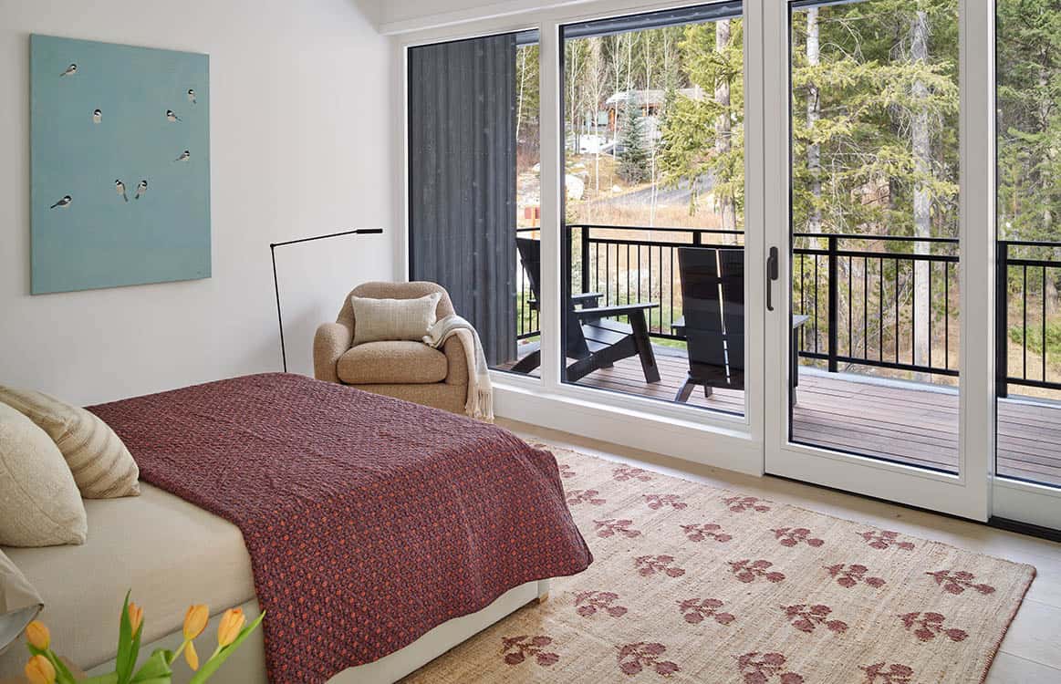 Guest bedroom with patterned bedding, tan armchair, and sliding doors to a private balcony