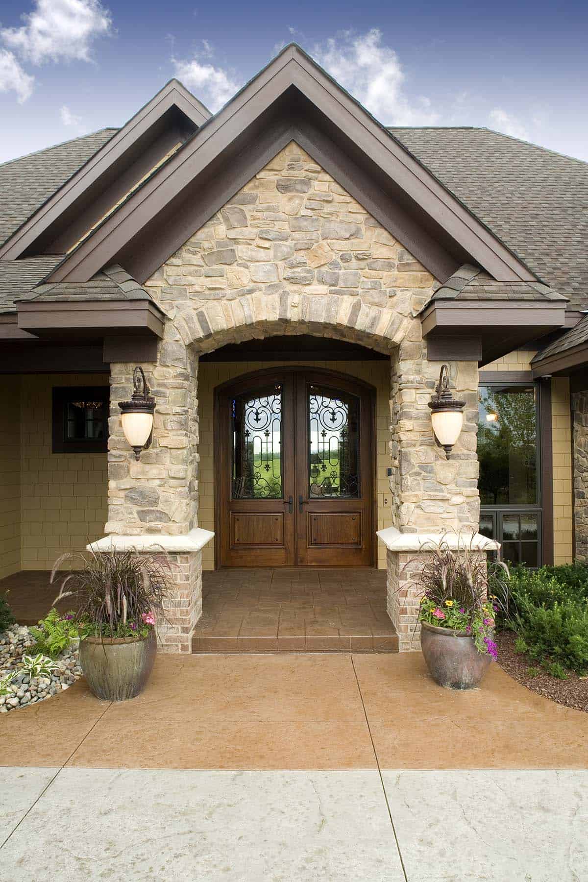 Arched stone entryway with wrought iron glass double doors