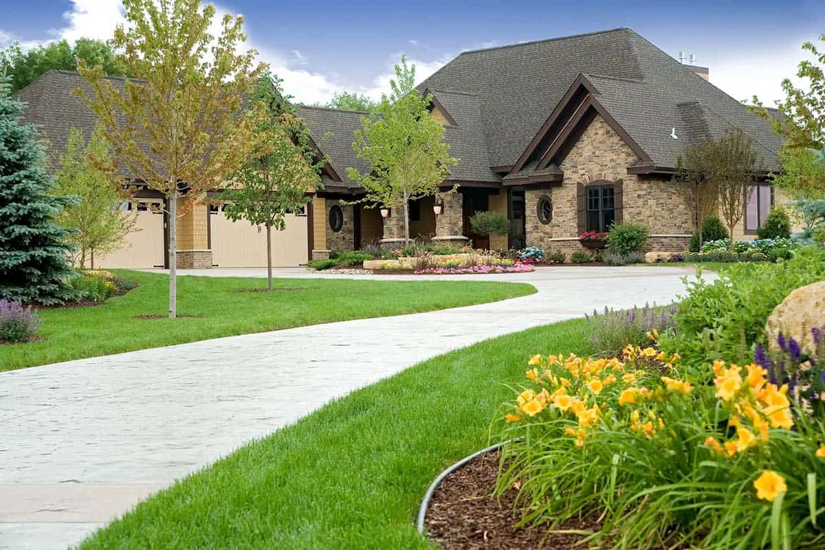 Front exterior of stone and shingle home with curved driveway and landscaping