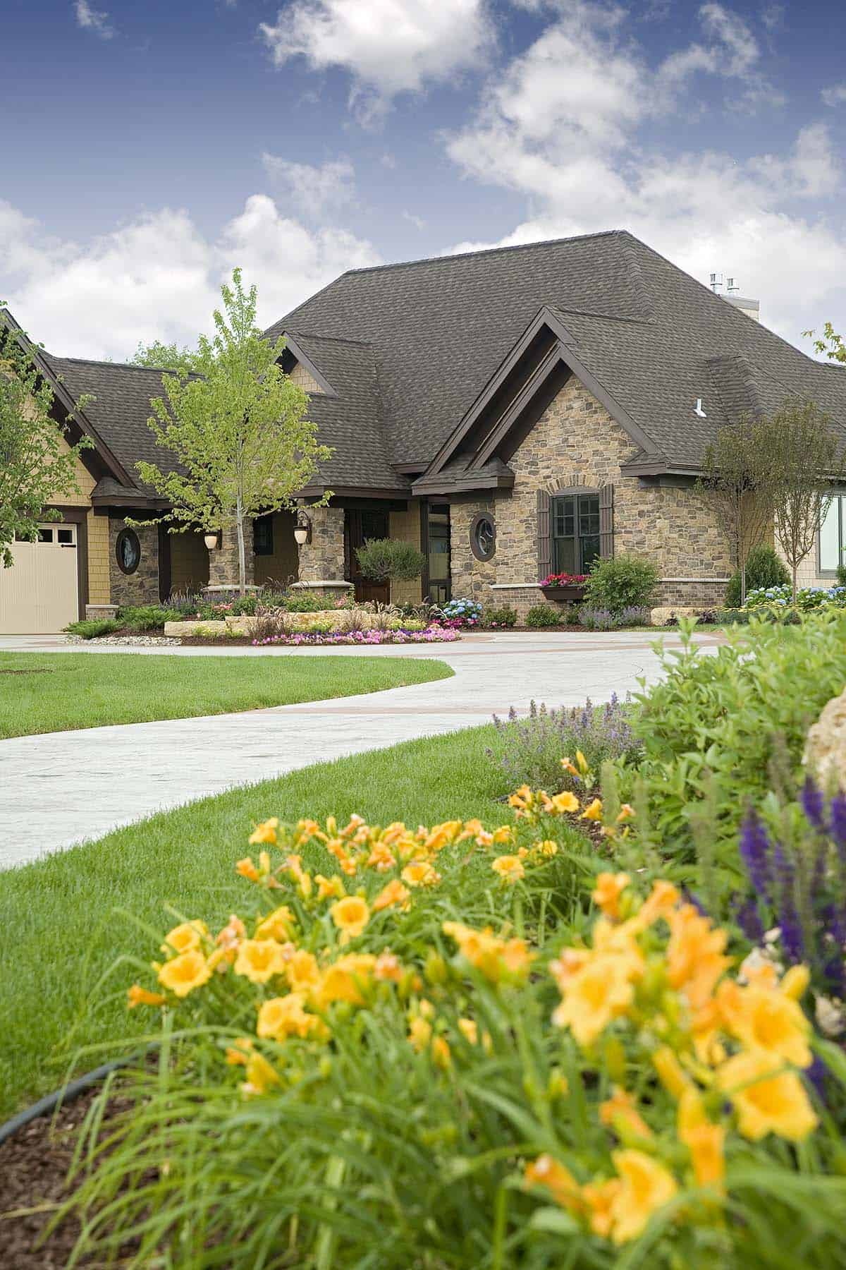 Luxury home front elevation with daylilies and curved concrete driveway
