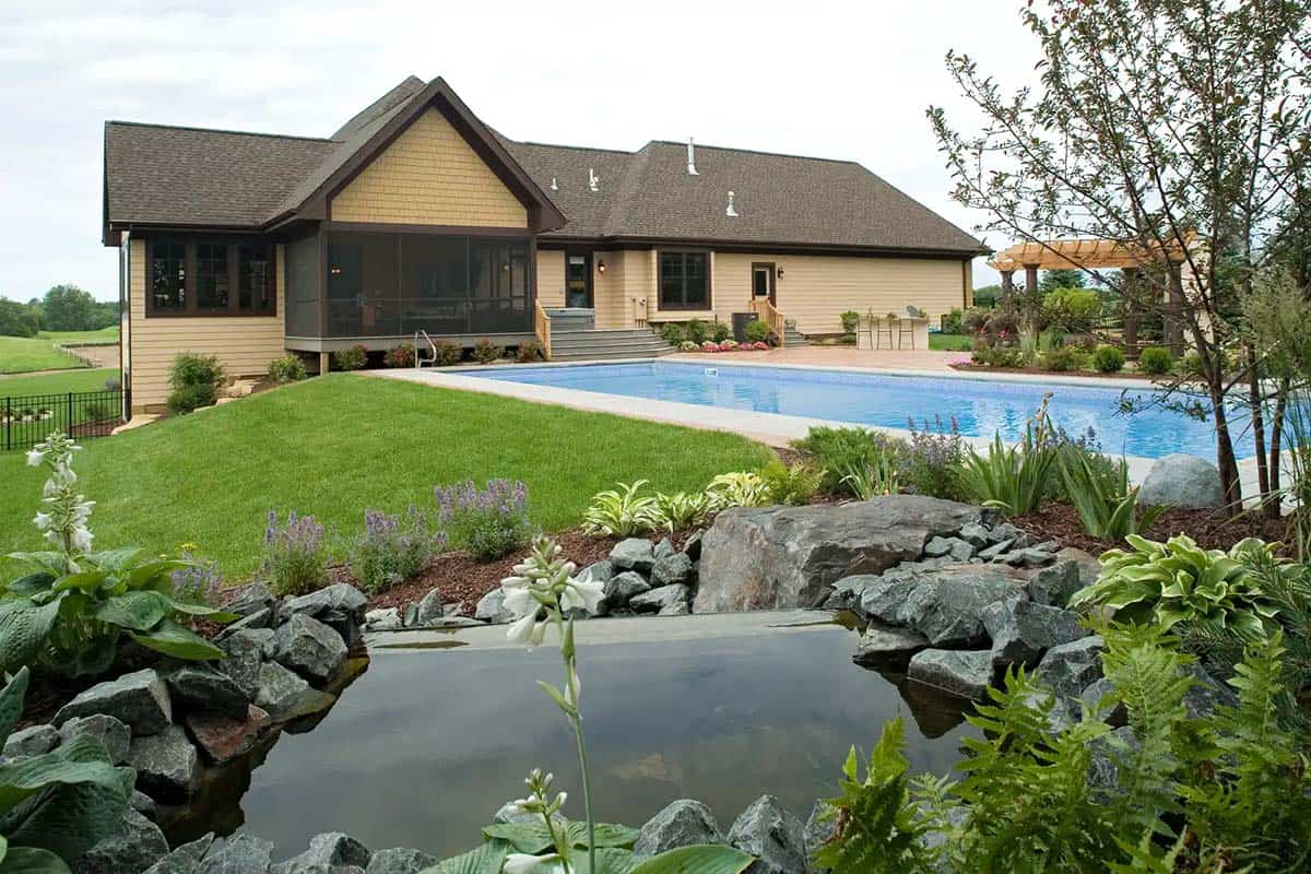 Rear exterior of home with pool, hot tub, and rock water feature