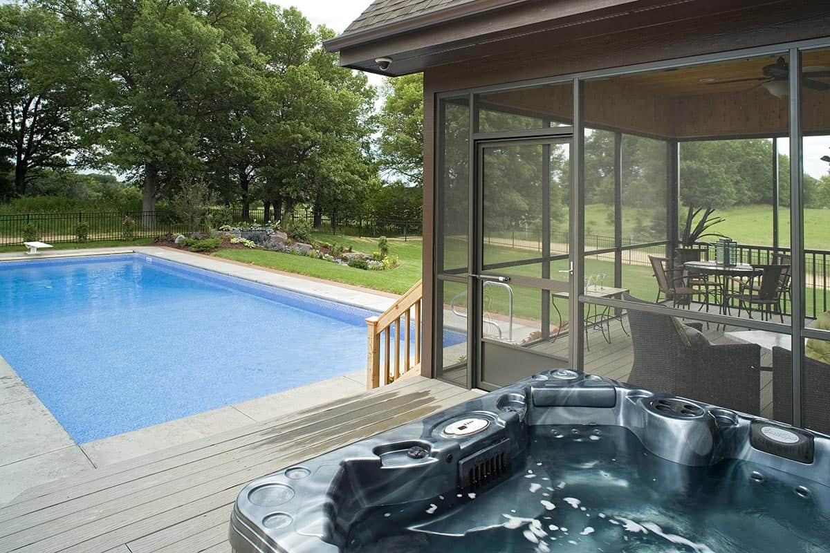 Pool deck with hot tub and screened porch seating area