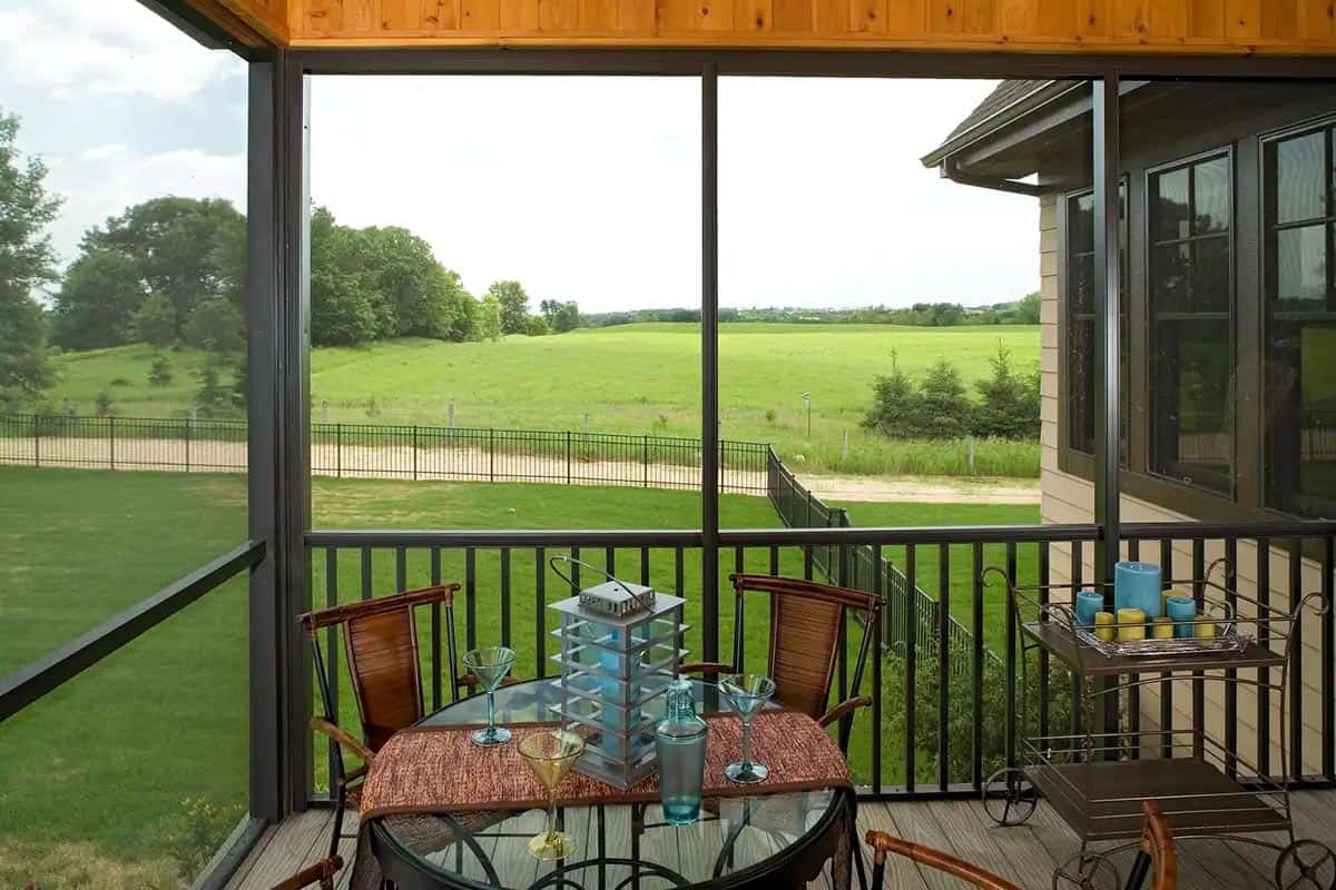 Screened porch seating area with cocktail table and farmland view