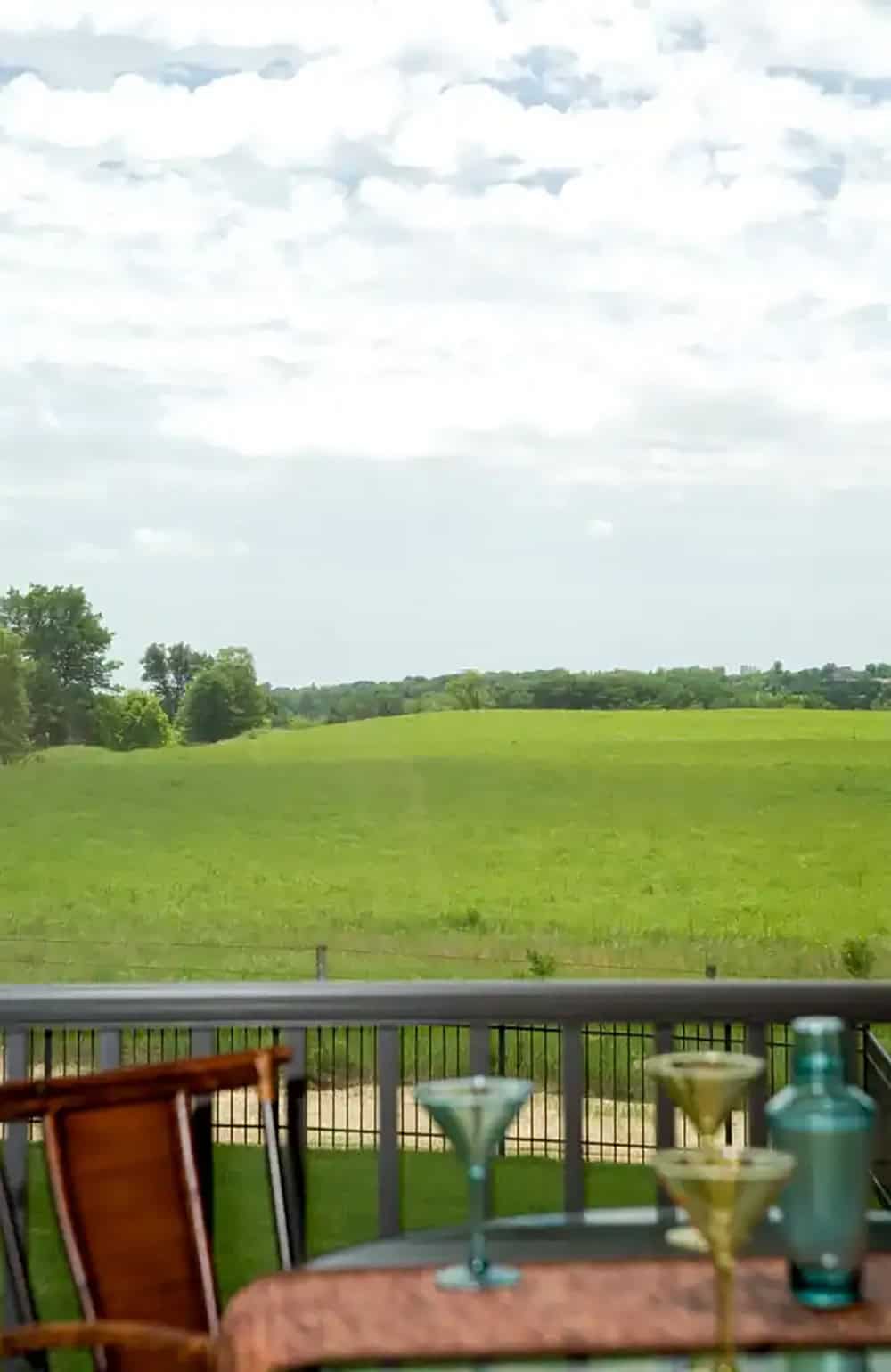 Martini glasses on porch table with rolling green field backdrop