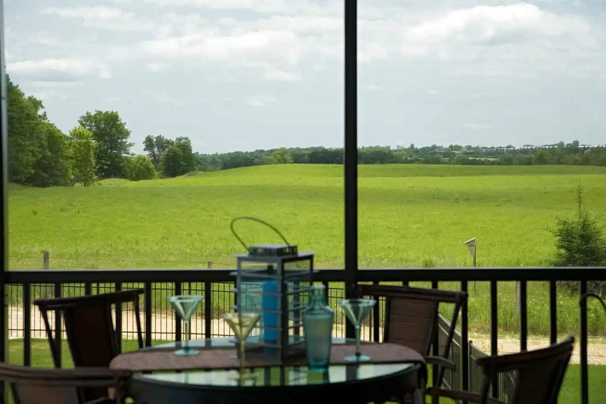 View through screened porch of table setting and open meadow