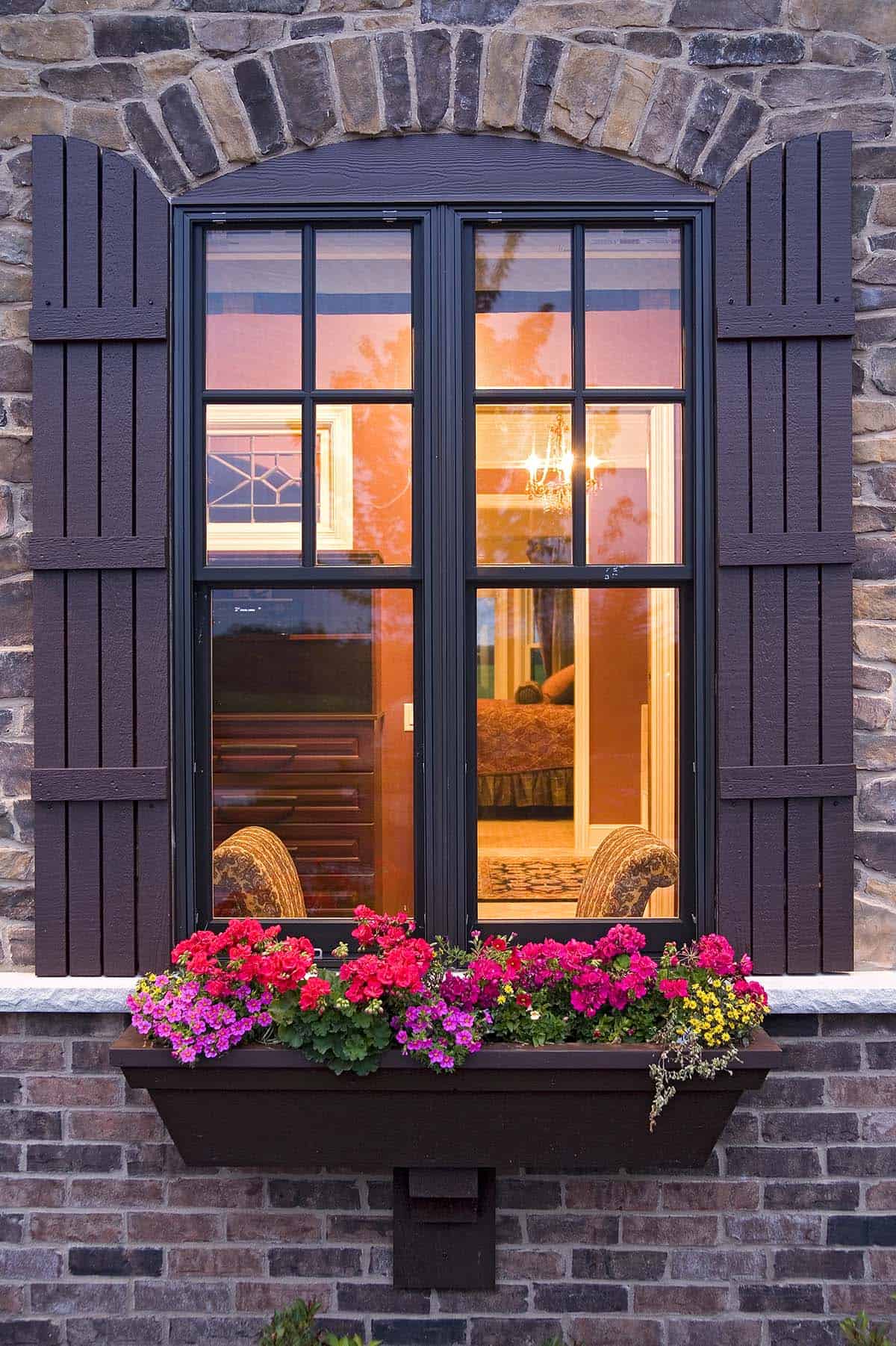 Bedroom window with flower box and stone surround at twilight