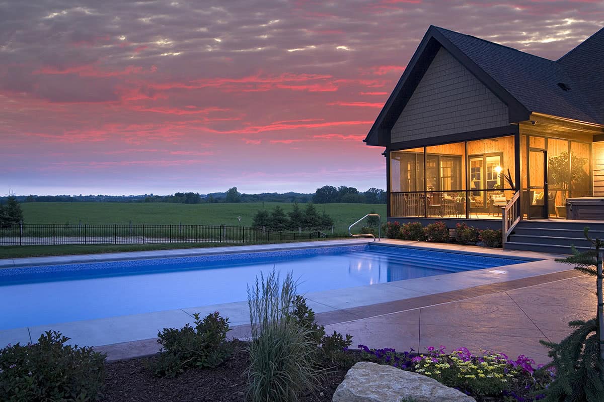 Backyard pool at sunset with pink clouds over open farmland