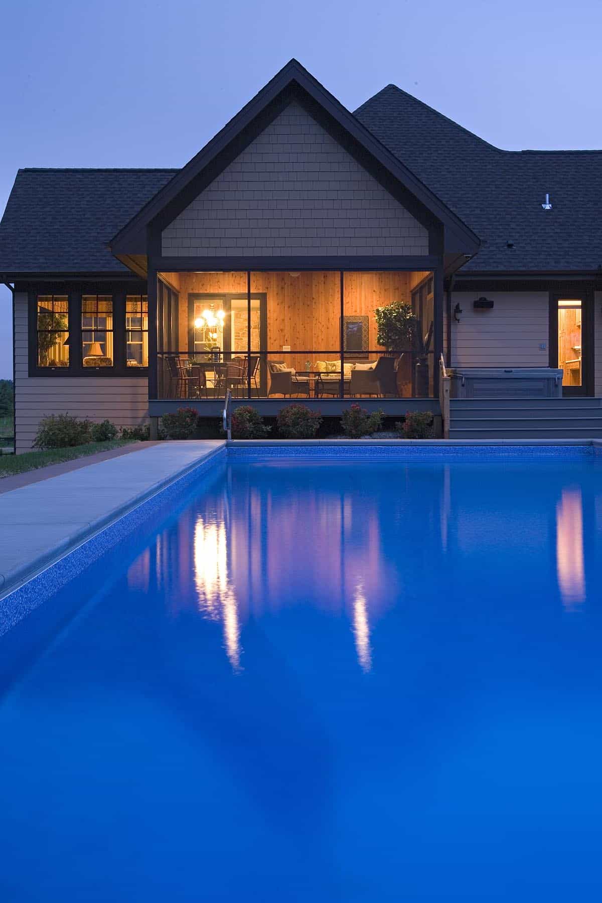 Illuminated screened porch reflected in swimming pool at dusk