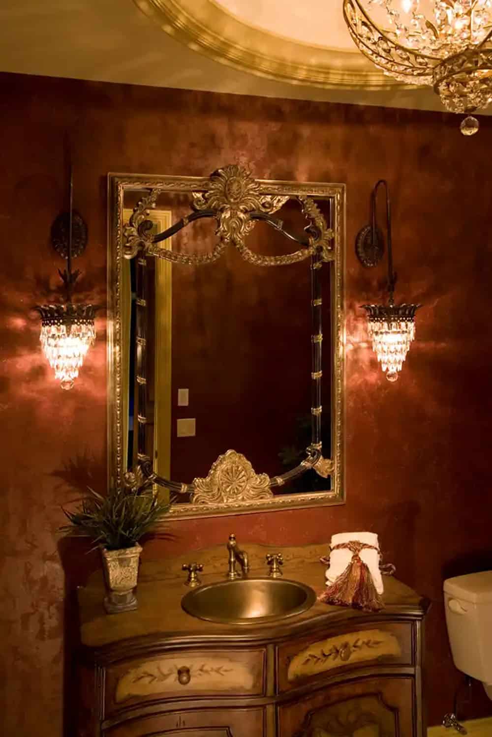 Ornate powder room vanity with gilded mirror and crystal sconces