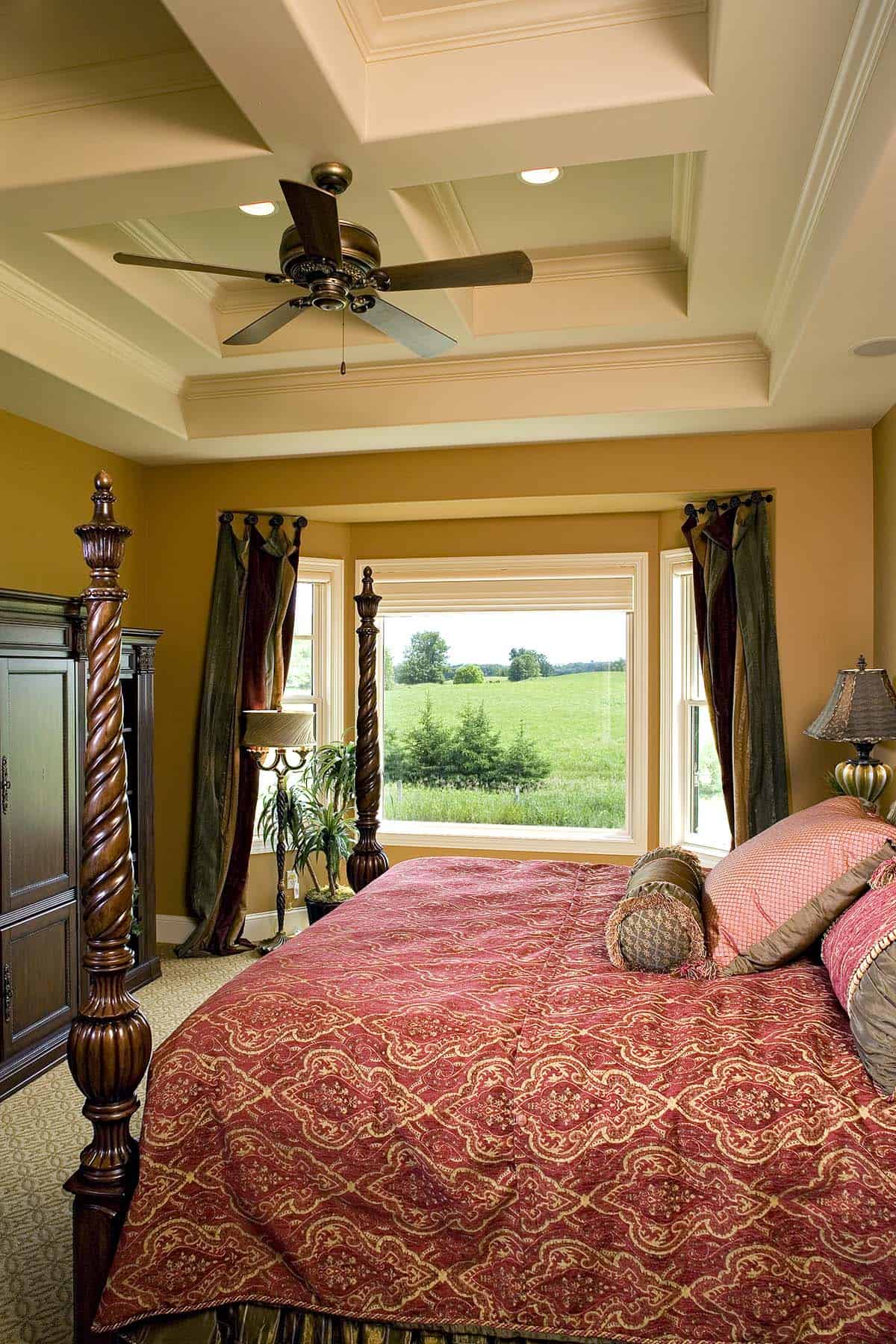 Primary bedroom with coffered ceiling and four-poster bed facing bay window