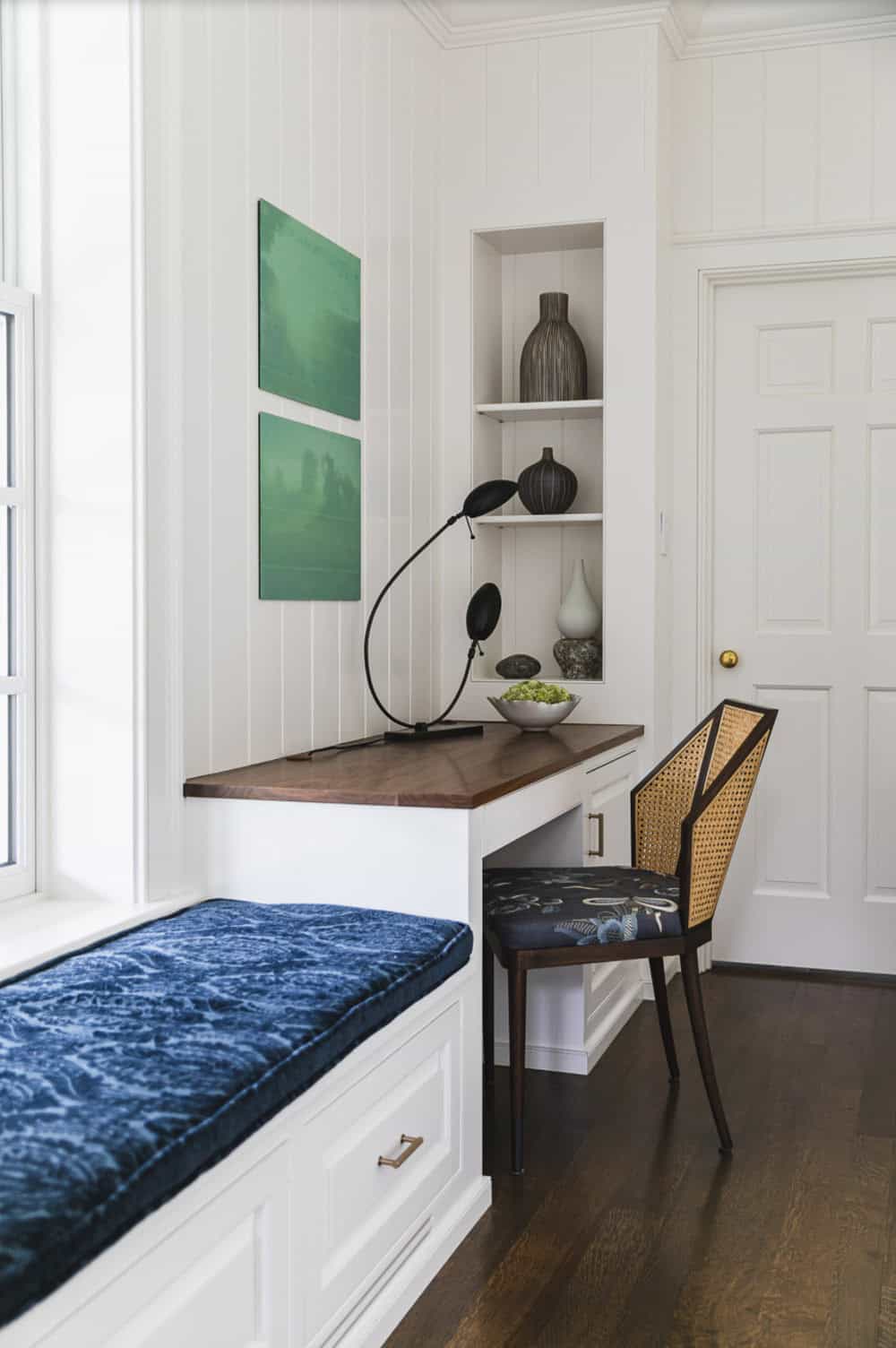 Close view of the built-in desk and window seat with green artwork and sculptural lamp