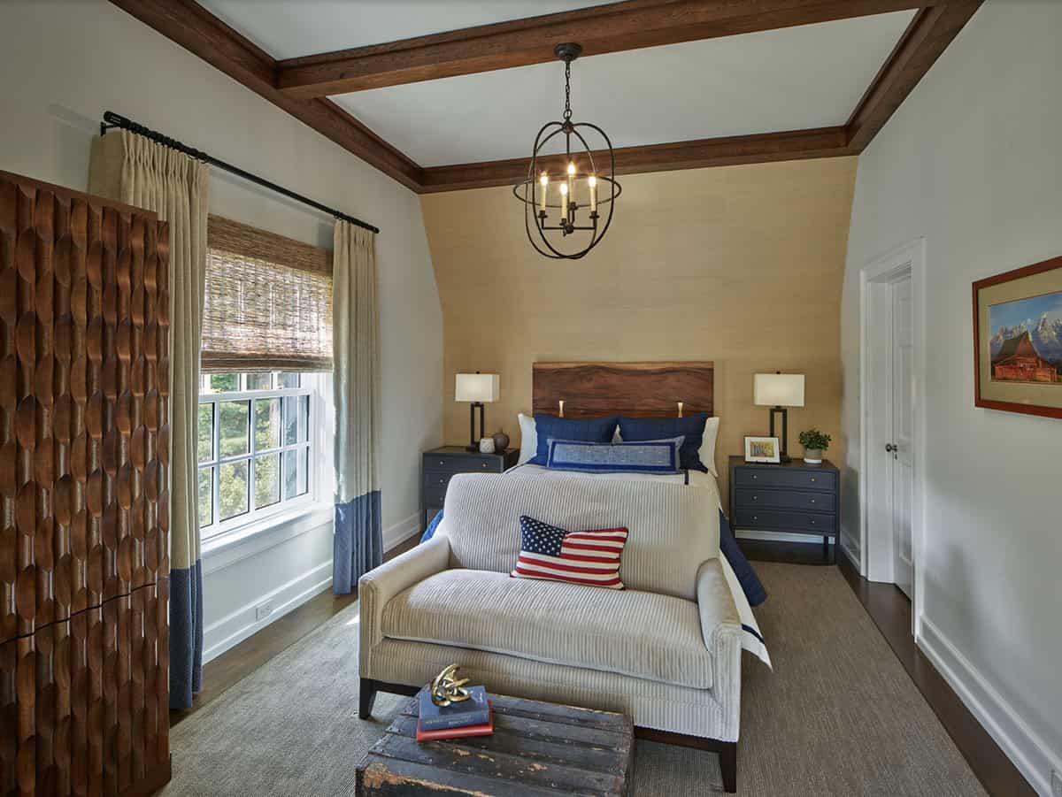 Bedroom with wood-beamed ceiling, grasscloth walls, and American flag throw pillow