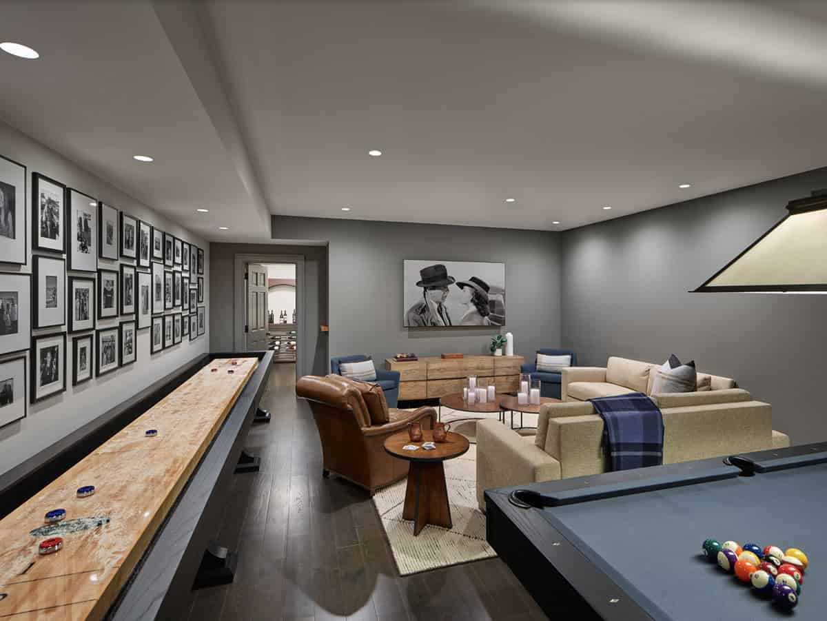 Basement game room with shuffleboard table, pool table, and gallery wall of black-and-white photos