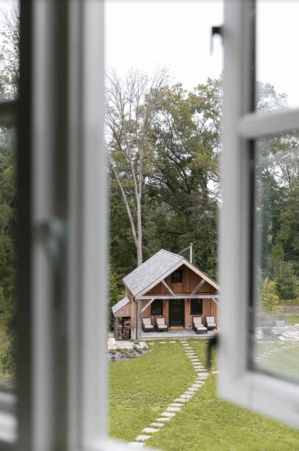 View through open window of a rustic timber-frame guest cabin across the lawn