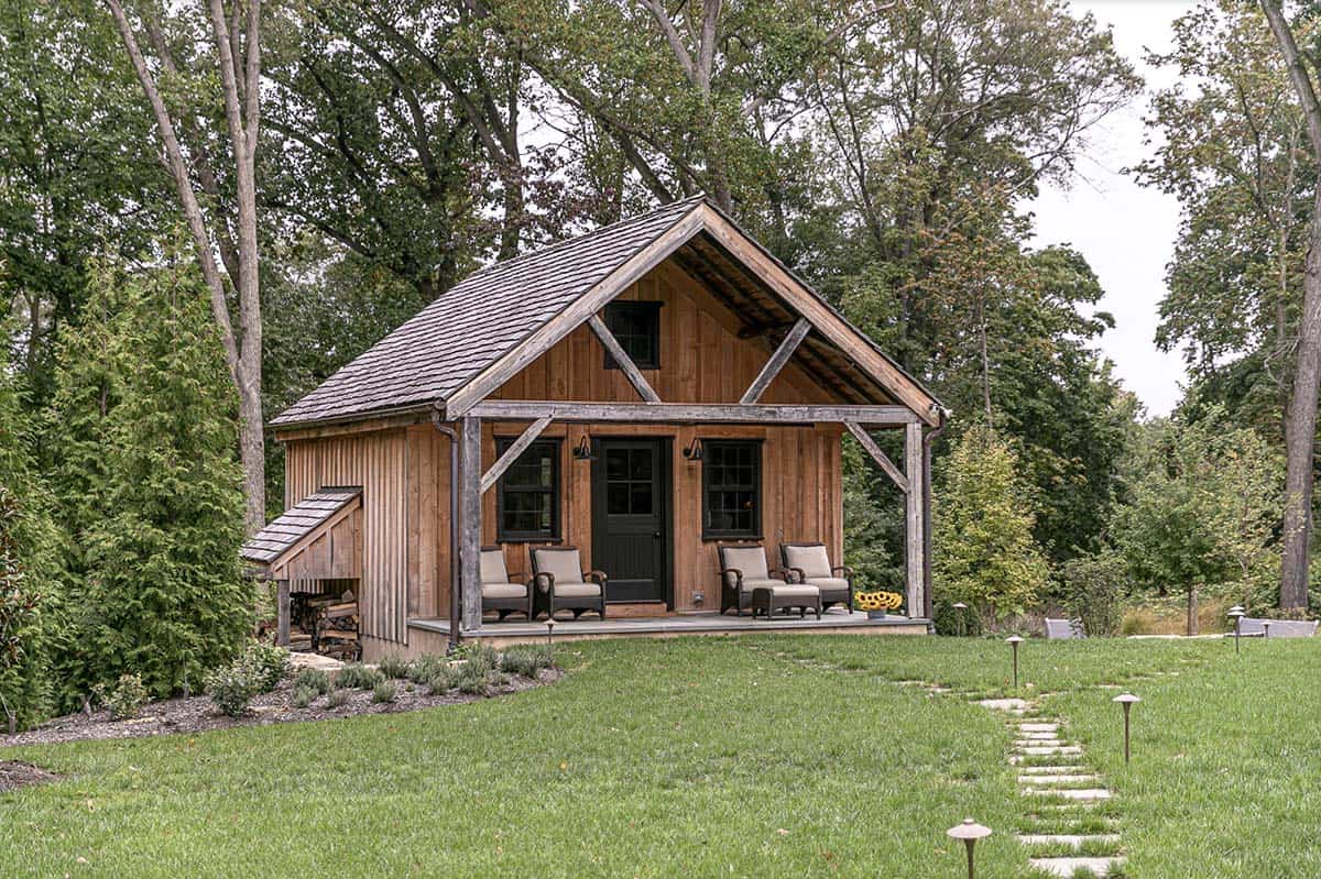 Rustic wood guest cabin with covered porch, timber framing, and stone path