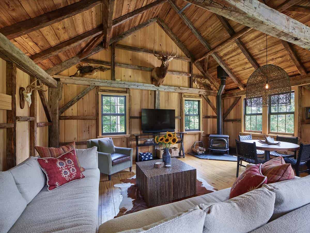 Rustic cabin great room with vaulted timber-frame ceiling, mounted elk, and wood stove