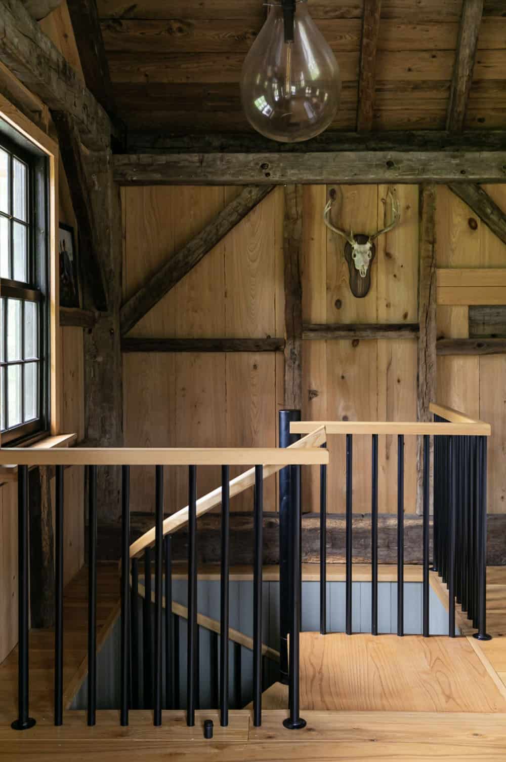 Open staircase landing in the cabin with exposed beams and mounted deer skull