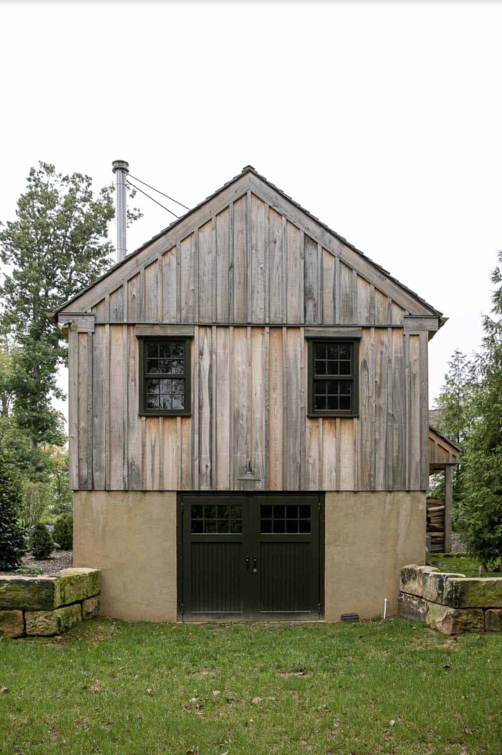 Rear gable end of the guest cabin showing wood siding, stucco base, and double carriage doors