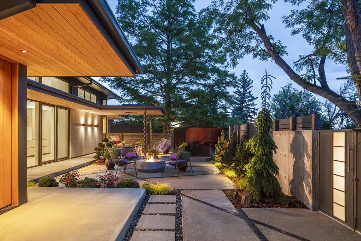 Covered patio with wood ceiling overlooking a fire pit lounge area and corten steel gate at twilight