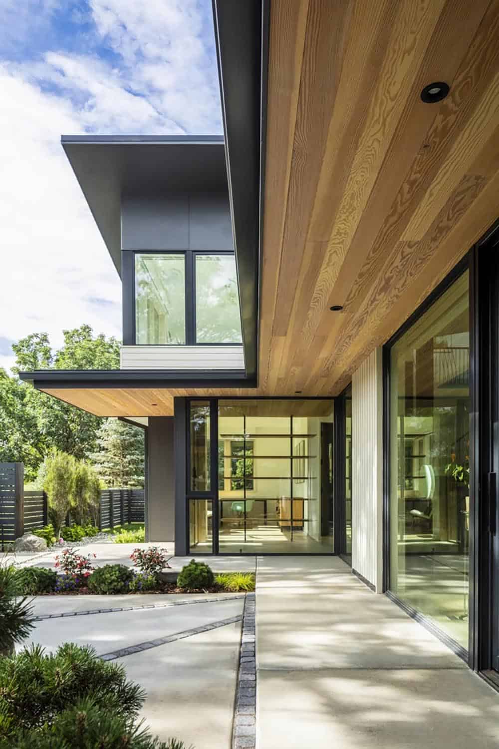 Exterior corner detail of a modern home with cedar-lined overhangs and black-framed glass walls
