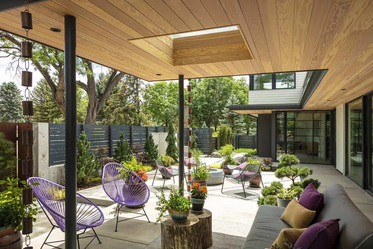 Covered outdoor lounge with purple woven chairs, gray sofa, and hanging copper rain chain