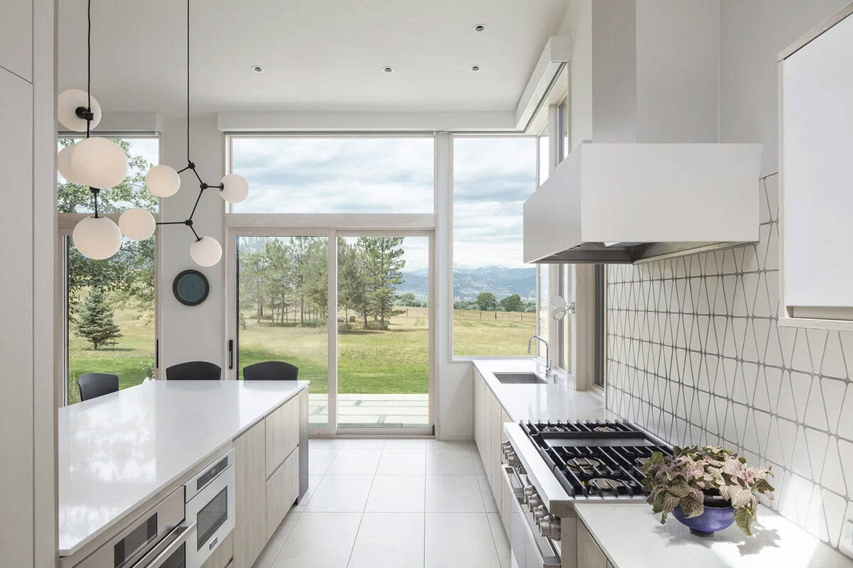 Galley kitchen with white countertops, patterned tile backsplash, and sliding glass door framing a mountain view
