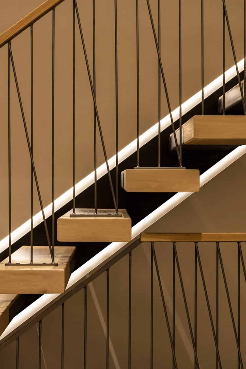 Close-up of a floating wood-step staircase with black metal railings and integrated LED strip lighting