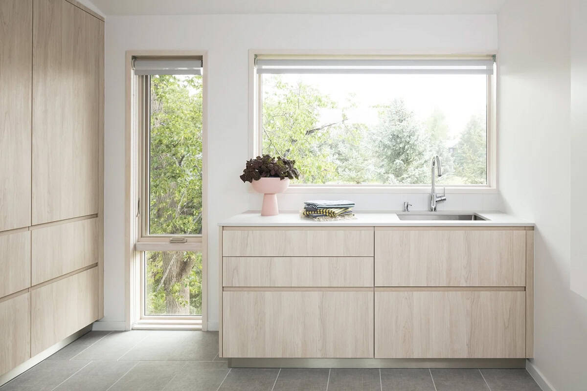 Minimalist kitchen nook with light wood cabinetry, stainless sink, and window overlooking greenery